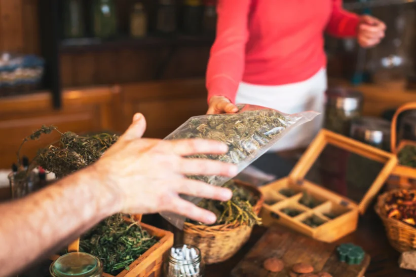 A budtender giving a cannabis flower to another person