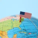 the American flag and a weed leaf stuck in a surface of the US map