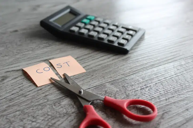 A calculator, scissor, and post-it with a note "cost" 