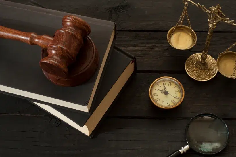 A gavel on top of black books with a balance symbol erected on the side