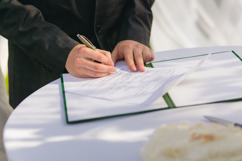 A man affixing his signature on license application documents